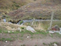 Recycled car bolstering bridge. Wee waterfall behind.